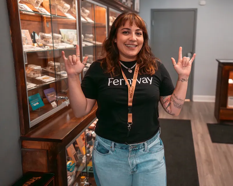 Budtender smiling in front of the wooden display cases