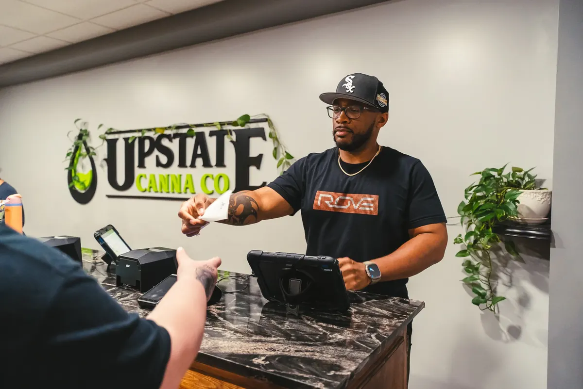 A budtender checks a customer’s ID at the Upstate Canna Co. counter